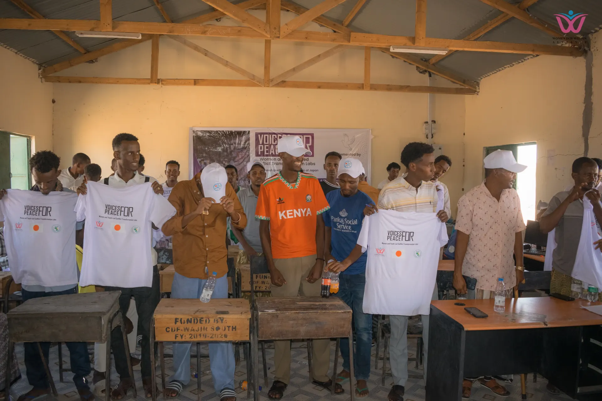 Young participants holding up Women for Women Alliance t-shirts in a workshop